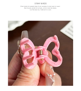 Gros plan d'une pince à cheveux papillon rose en forme de cœur tenue dans la main