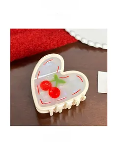 Detail of cream heart hair claw with cherry pattern on a wooden surface