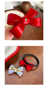 Detail of red acetate bow hair clip and elastic tie with rhinestone and marble texture