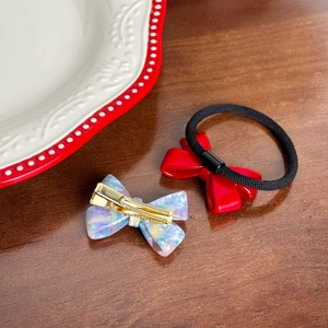 Red bow hair tie and marble acetate bow hair clip set on a dark wooden background