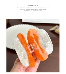 Detail of cute orange acetate shark hair claw clip with glossy marbled pattern texture