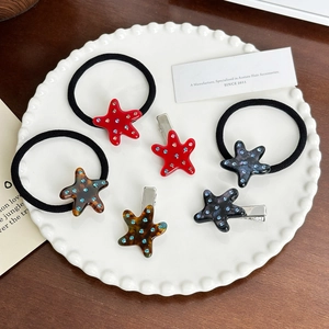 Lot d'accessoires pour cheveux en acétate avec étoiles et strass sur plateau coquillage