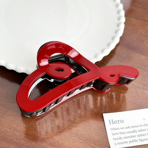 Elegant cherry red heart-shaped hair claw clip on a rustic wooden table setting