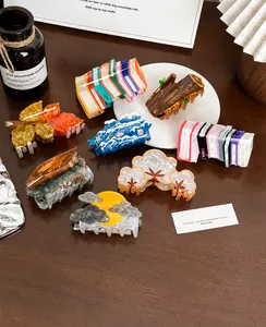 Detailed view of various acetate hair claws in creative book and leaf shapes on wood desk