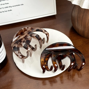 Large tortoiseshell and leopard hair claws displayed on a decorative white plate