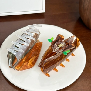 Large acrylic hair claws featuring marble and wood grain patterns on a ceramic plate