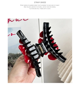 Detail showing hand holding a 10cm black resin hair claw with red heart pattern