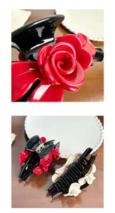 Close-up of vintage floral claw clips with red rose and cream flower on glossy black base