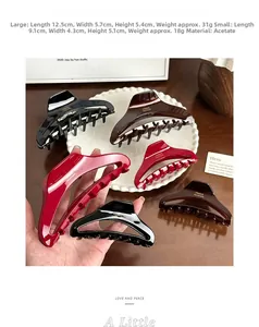 Close-up of acetate shark hair clips in large and small sizes with golden logo detail