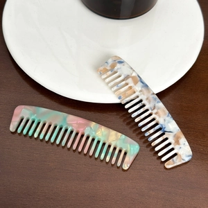 Elegant wide-tooth acetate hair combs with marble patterns on a wooden table