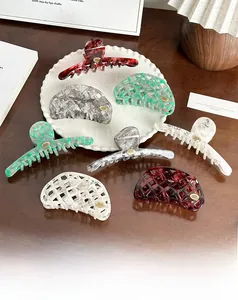 Macro shot of assorted hollow acetate hair claws in various marble patterns on a ceramic plate