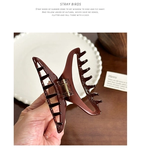 Close-up of a dark brown butterfly hair claw clip showing glossy resin texture and metal spring