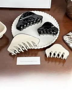 Close-up of acetic acid hair claws in black and beige on a decorative pearl tray