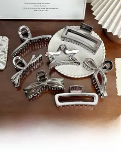 Detailed close-up of metallic silver hair clips in star and butterfly shapes on a white tray