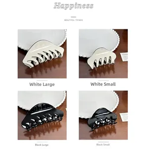Macro detail of large and small acetate hair claws in black and cream on a vintage tray