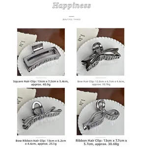 Detail of four large silver metal hair claws in various elegant geometric shapes