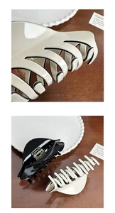 Detail view of large acetate hair claws in black and cream white with strong metal springs