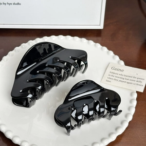 Polished black acetate hair claw set including large and medium clips on a decorative plate