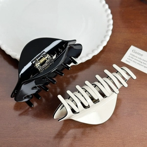 Set of minimalist glossy acetate hair claws in black and cream on a wooden desk