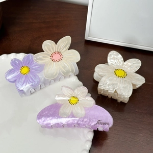 Elegante florale Macaron-Haarklammern in Lila und Beige auf einem Holztisch