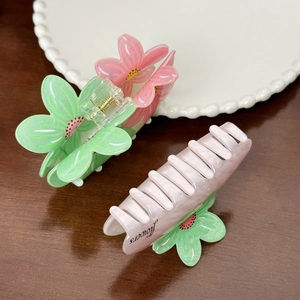 Florale Haarklammer in Pastellrosa und Minzgrün im Macaron-Stil auf Holztisch
