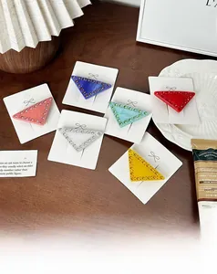 Gros plan de six barrettes triangulaires colorées avec strass sur carte de présentation