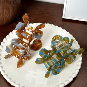 Elegant acetate butterfly hair claws with marble texture in ceramic bowl on wood desk