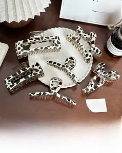 Detailed view of five black and white cow print hair claws in various geometric shapes