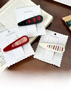 Set of three vintage water drop hair clips with marble and plaid patterns on an English book