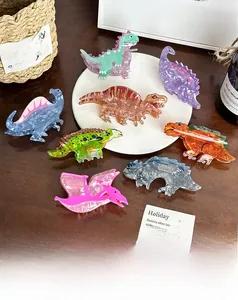 Makroaufnahme bunter Haarklammern aus Acryl in Dinosaurierform mit Marmortextur auf Holz