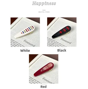 Detail view of woven fabric hair clips in white, black and red colors with embroidery