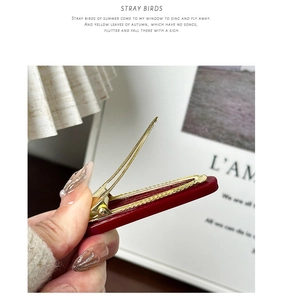 Detail view of burgundy resin hair clip with golden metal spring clip mechanism