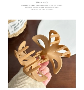 Detail showing matte hollow egg flower hair claw clip in earthy beige resin material
