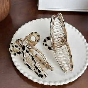 Elegant resin hair claw clips with cow print pattern on decorative white tray display