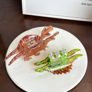 Süße Acryl-Haarklammern in Dinosaurier-Form als T-Rex und Langhals auf weißem Teller