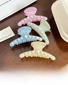 Close-up of shell-shaped acetate hair claws with pearls in pink green blue and yellow