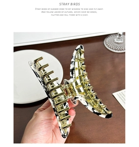 Detailed close-up of marble pattern hair claw clip with strong golden metal teeth