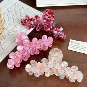 Three acetate flower hair claws with rhinestones and marble textures on desk