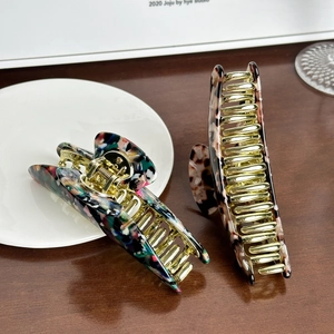 Set of two large acetate hair claws in marble and tortoiseshell patterns on wood