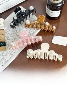 Detailed view of four large pearl hair claw clips in black, tortoise, pink, and cream white
