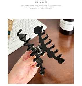 Glossy black large acetate hair claw clip held by hand showing strong metal spring