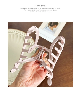 Close-up of pink butterfly hair claw clip with interlocking teeth for hair styling
