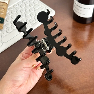 Oversized black acetate shark hair claw clip for thick hair styling in life-style scene