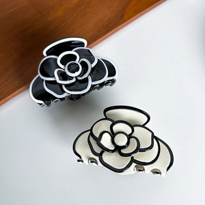 Elegant acetate camellia hair claw clips in black and cream white with contrast edges