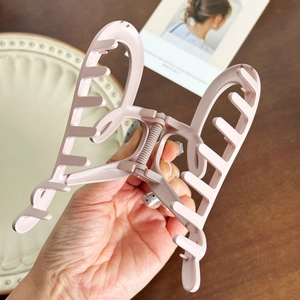 Large pink matte butterfly hair claw clip for women shown in a detailed hand-held view