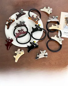 Détail de pinces à cheveux et élastiques motif chien en acétate sur un plateau blanc