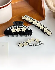 Détail de pinces à cheveux avec fleurs crème, perles et strass sur acétate noir élégant