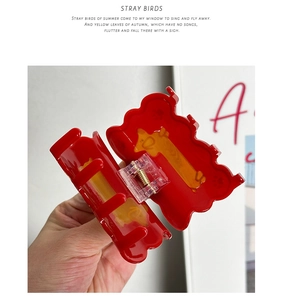 Detail of red acetate hair claw clip featuring a unique yellow giraffe pattern design