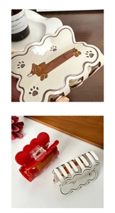 Macro view of wave-shaped acetate hair claw clips featuring dachshund dog illustrations