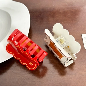 Acetate dachshund hair claw clips with wavy edges and golden paw prints in red and cream